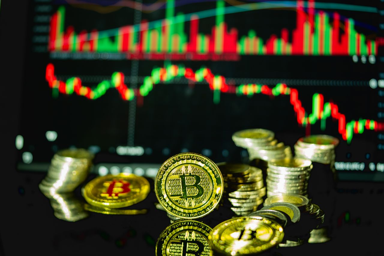 Golden bitcoins stacked in front of a fluctuating financial chart, symbolizing cryptocurrency trading.