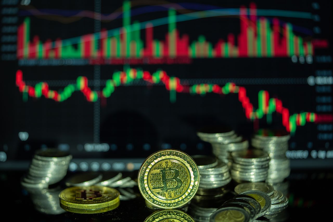 Golden Bitcoin and stacked coins in front of a colorful financial chart, symbolizing cryptocurrency market dynamics.